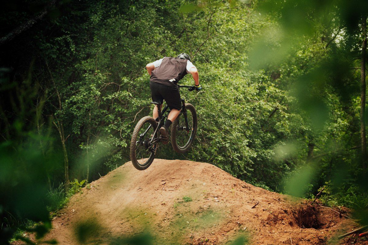 Mountain biker riding a dirt trail through green forest